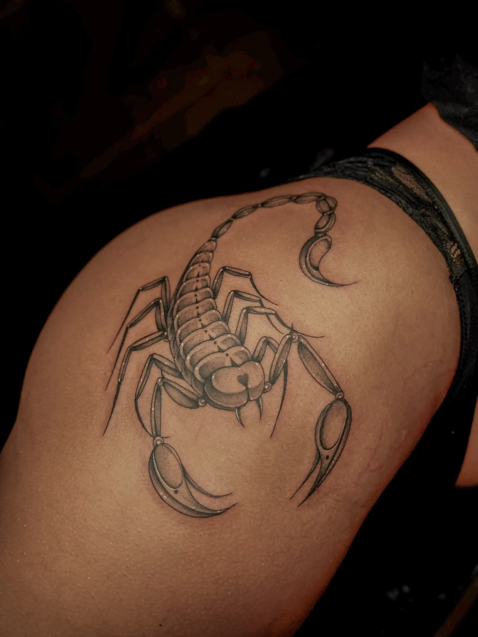 Black and grey scorpion tattoo on a hip.