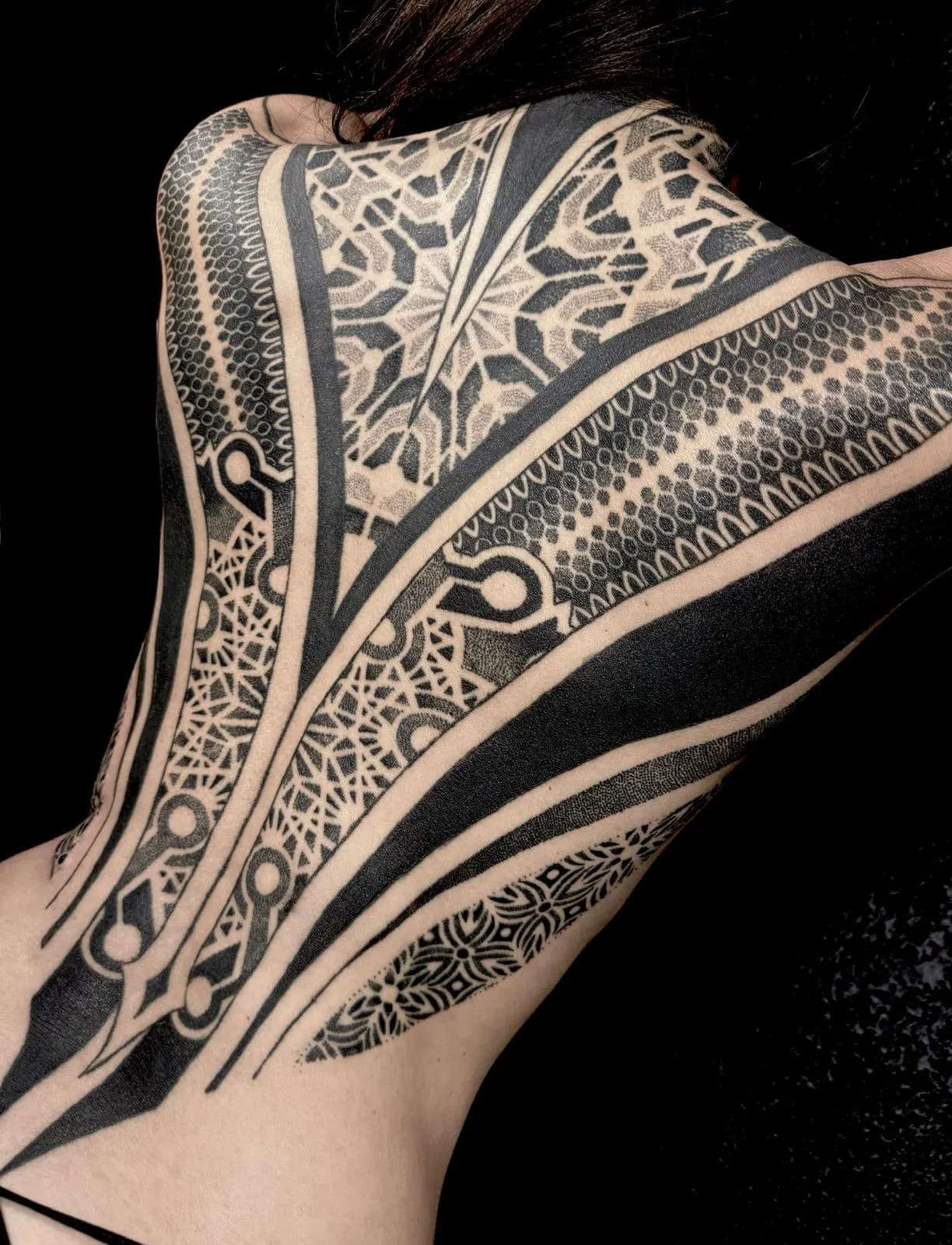 Ornamental blackwork tattoo covering a back and the back of a neck.