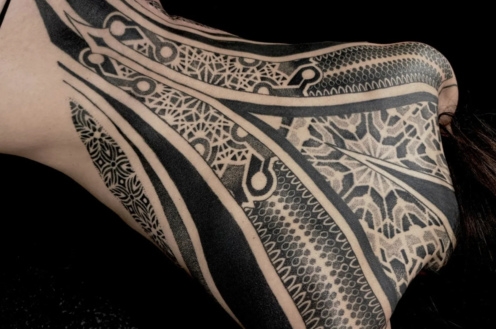 Large blackwork and dotwork ornamental tattoo covering a shoulder and neck.