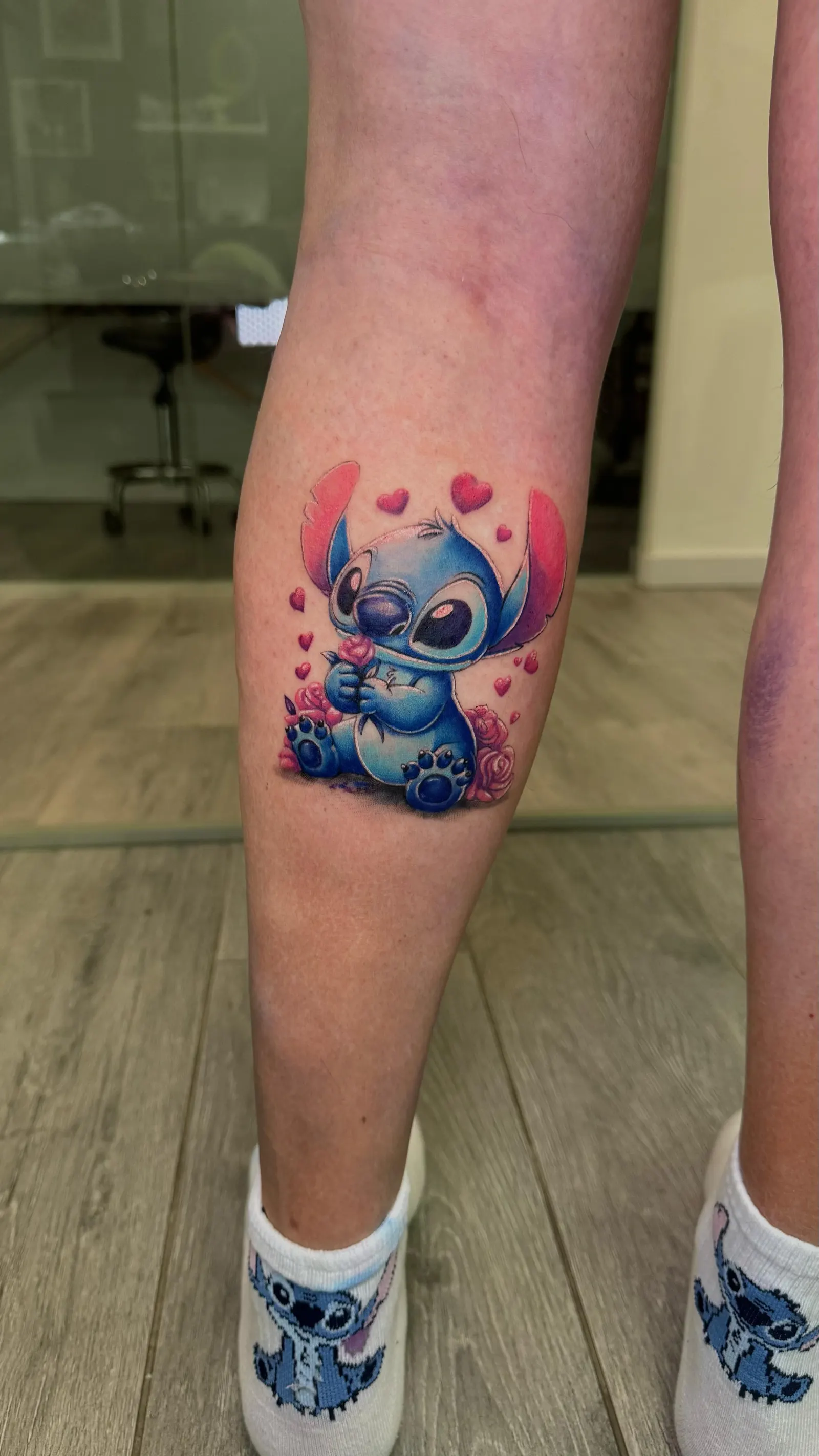 Colour cartoon character tattoo with hearts and roses on a calf.