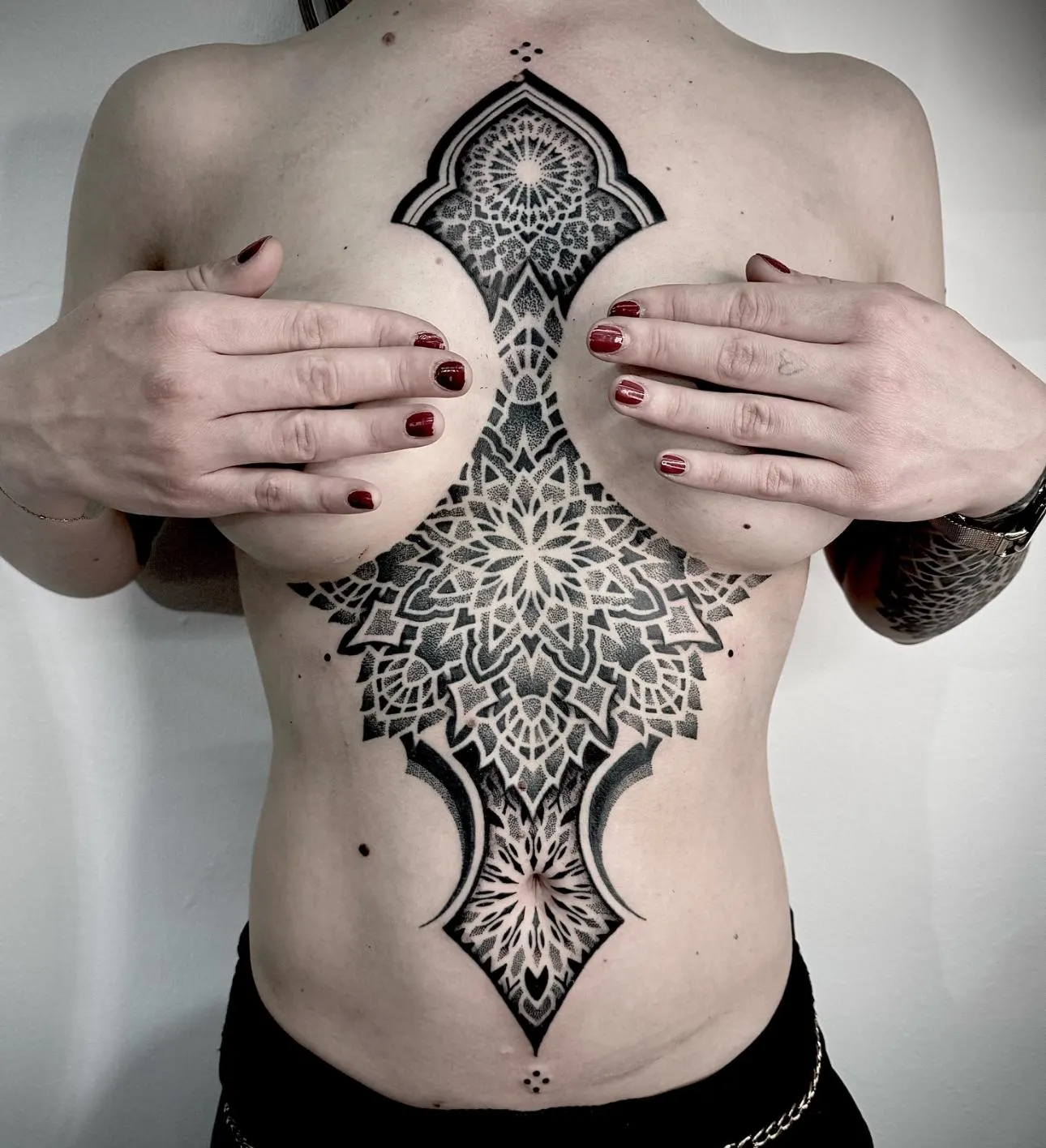 Symmetrical dotwork mandala tattoo running down the centre of a torso.