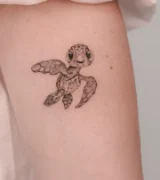 Fine line baby sea turtle arm tattoo