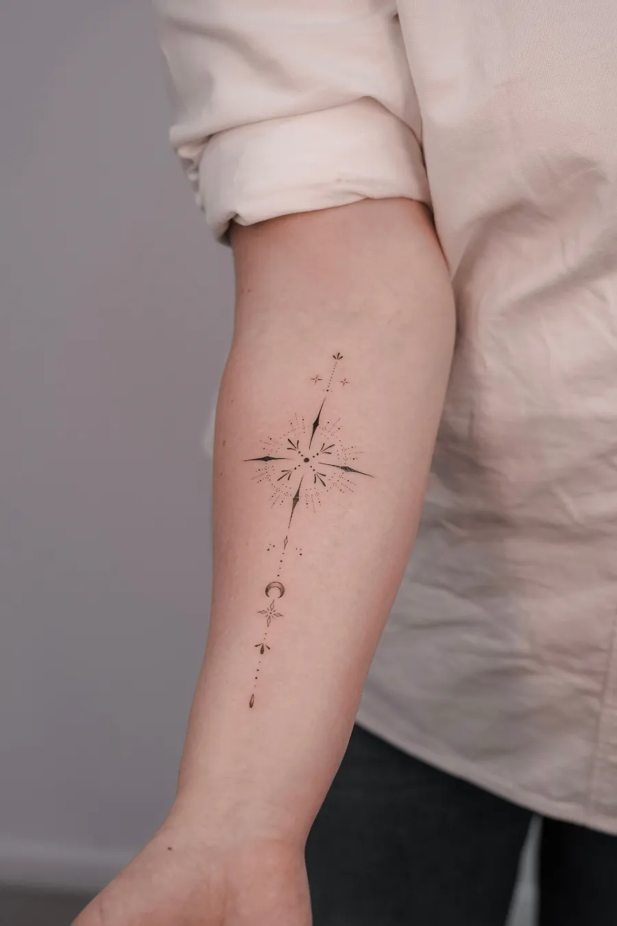 Ornamental fine line starburst forearm tattoo