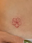 Small red-ink hibiscus tattoo on the hip